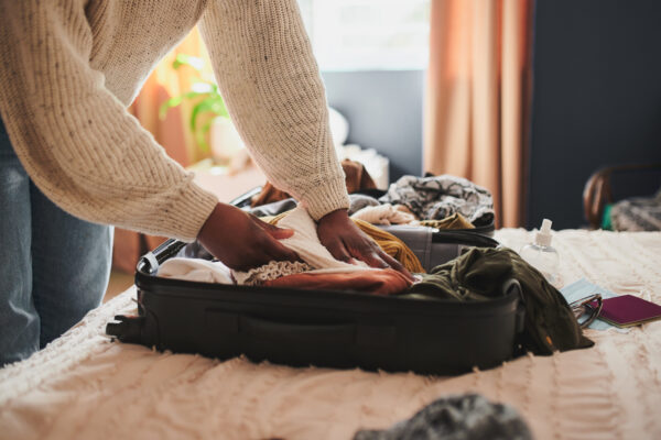 Woman packing her things into a suitcase for a vacation - Beacon Inn